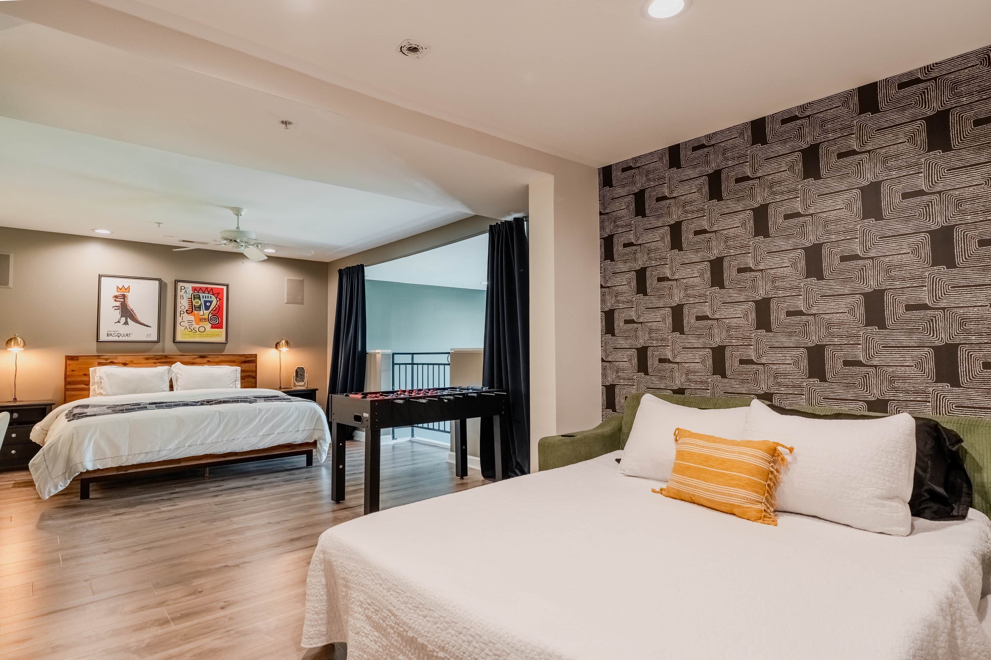 Une chambre d’hôtel avec deux lits, une table de baby-foot et un balcon.