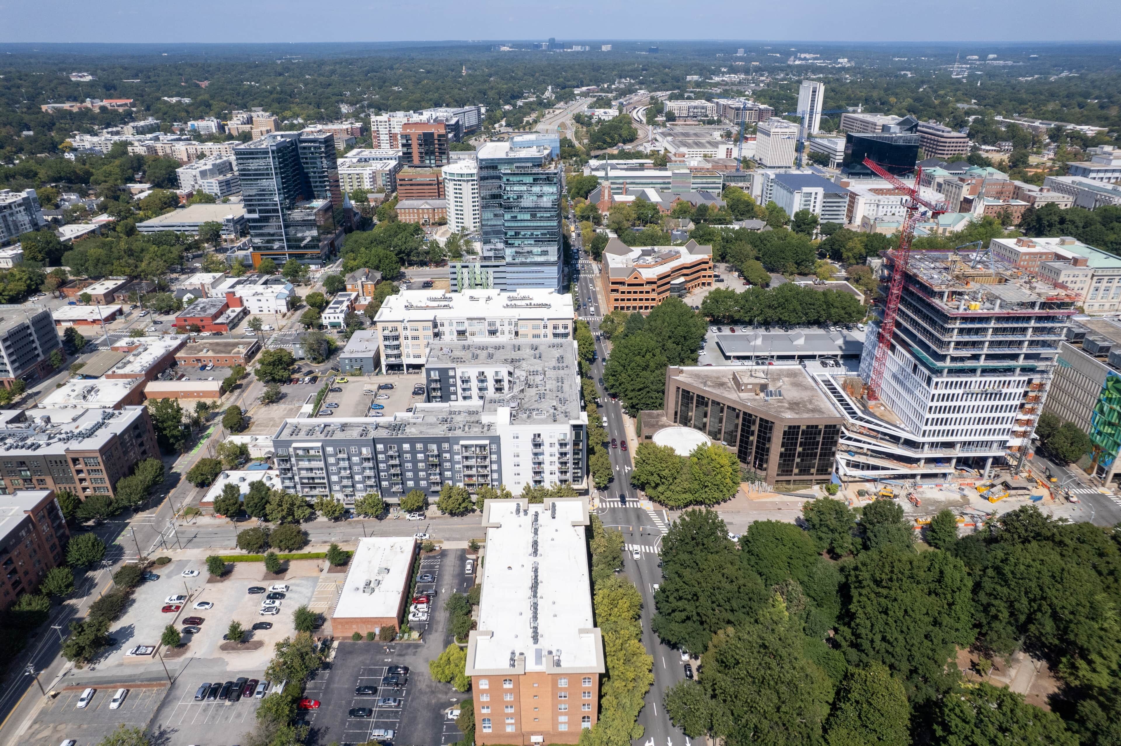 An aerial view of a cityscape with various buildings, roads, and greenery.