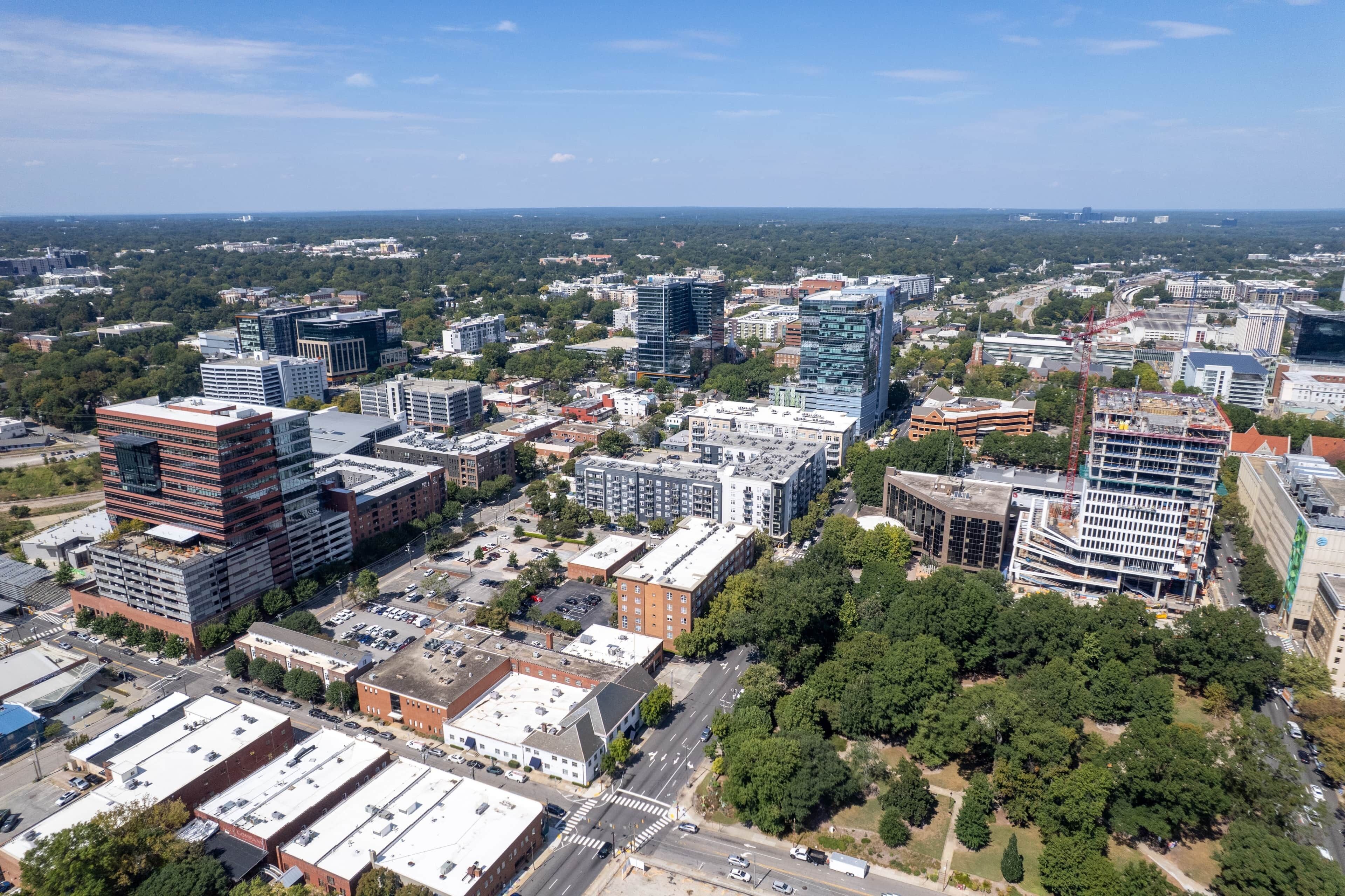 An aerial view of a cityscape with modern buildings, roads, and green spaces.
