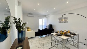 Un comedor moderno con suelo de mármol, una mesa de comedor con sillas y un espejo grande a la izquierda.