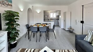En modern lägenhet med matplats, kök och vardagsrum.
