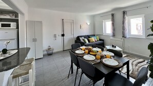 Ett modernt kök med matplats, vita skåp och en inbyggd mikrovågsugn.