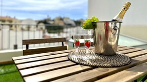 A metal bucket with a bottle of champagne, two glasses with strawberries, and a woven placemat on a wooden table outdoors. - CARVOEIRO TERRACE by HOMING (Carvoeiro)