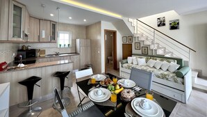 A modern kitchen with a dining area, a staircase, and a living room with a sofa. - CARVOEIRO TERRACE by HOMING (Carvoeiro)