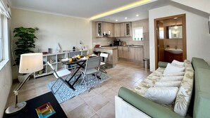 A compact living space with a dining area, kitchenette, and a sofa. - CARVOEIRO TERRACE by HOMING (Carvoeiro)