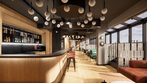 A modern bar area with a curved wooden counter, multiple hanging spherical lights, and a seating area with green and red upholstered chairs. - ASTON HOTEL RIGA (Riga)