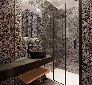 A modern bathroom with a black stone sink, a glass shower enclosure, and a terrazzo floor.