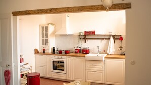 Une cuisine avec des armoires blanches, une poubelle rouge et un panneau accroché au mur.