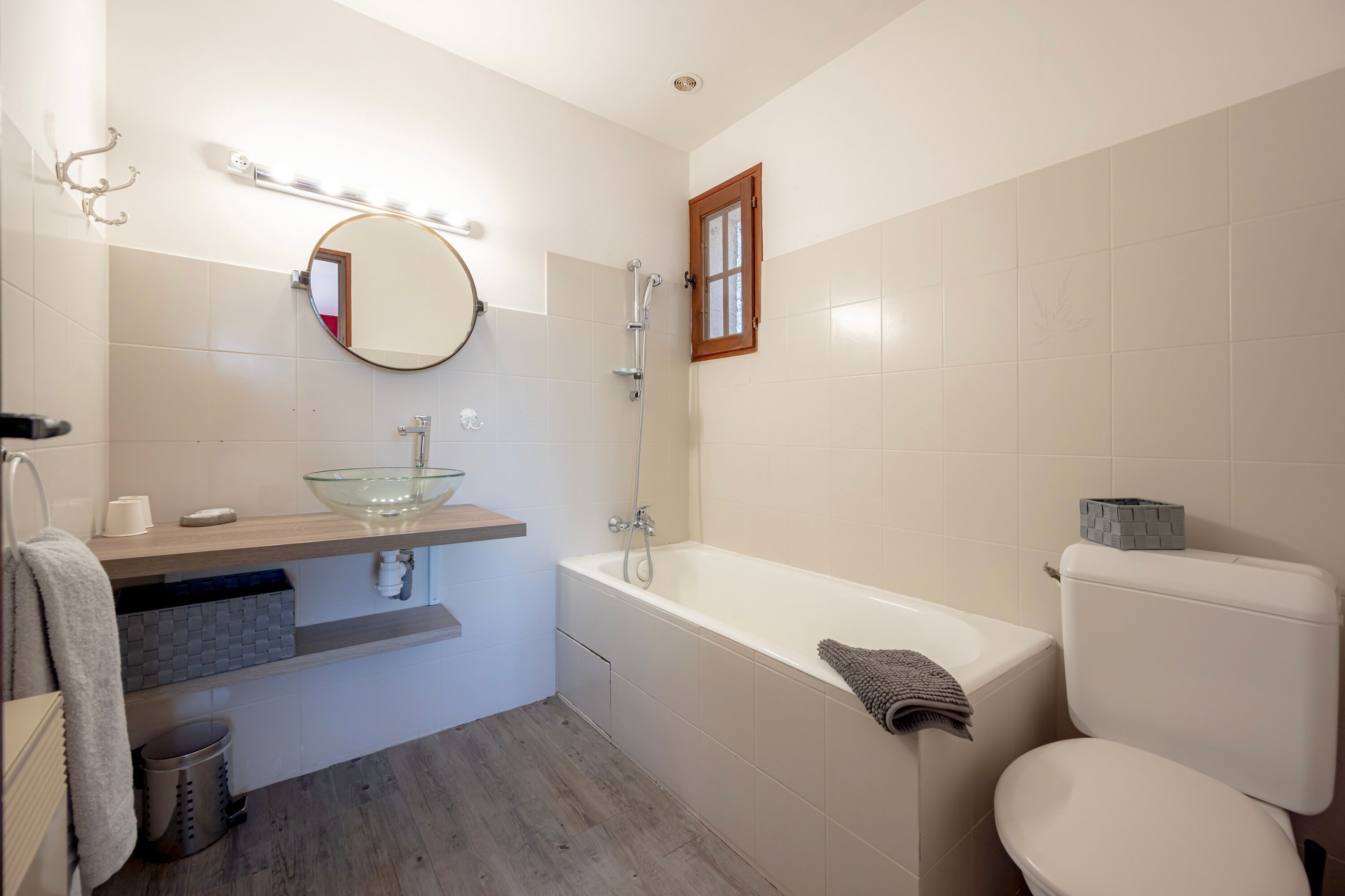 Un bagno con un lavabo in vetro, una vasca, un water e uno specchio.