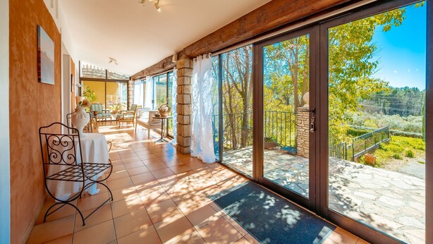 A spacious balcony with a view of a garden and trees.