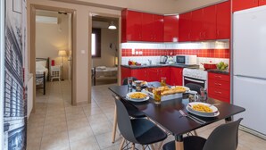 A modern kitchen with red cabinets, a dining table with chairs, and a refrigerator.