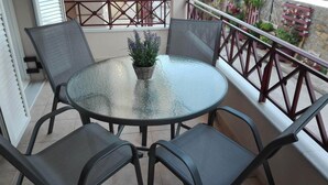 A round glass table with four chairs on a balcony.