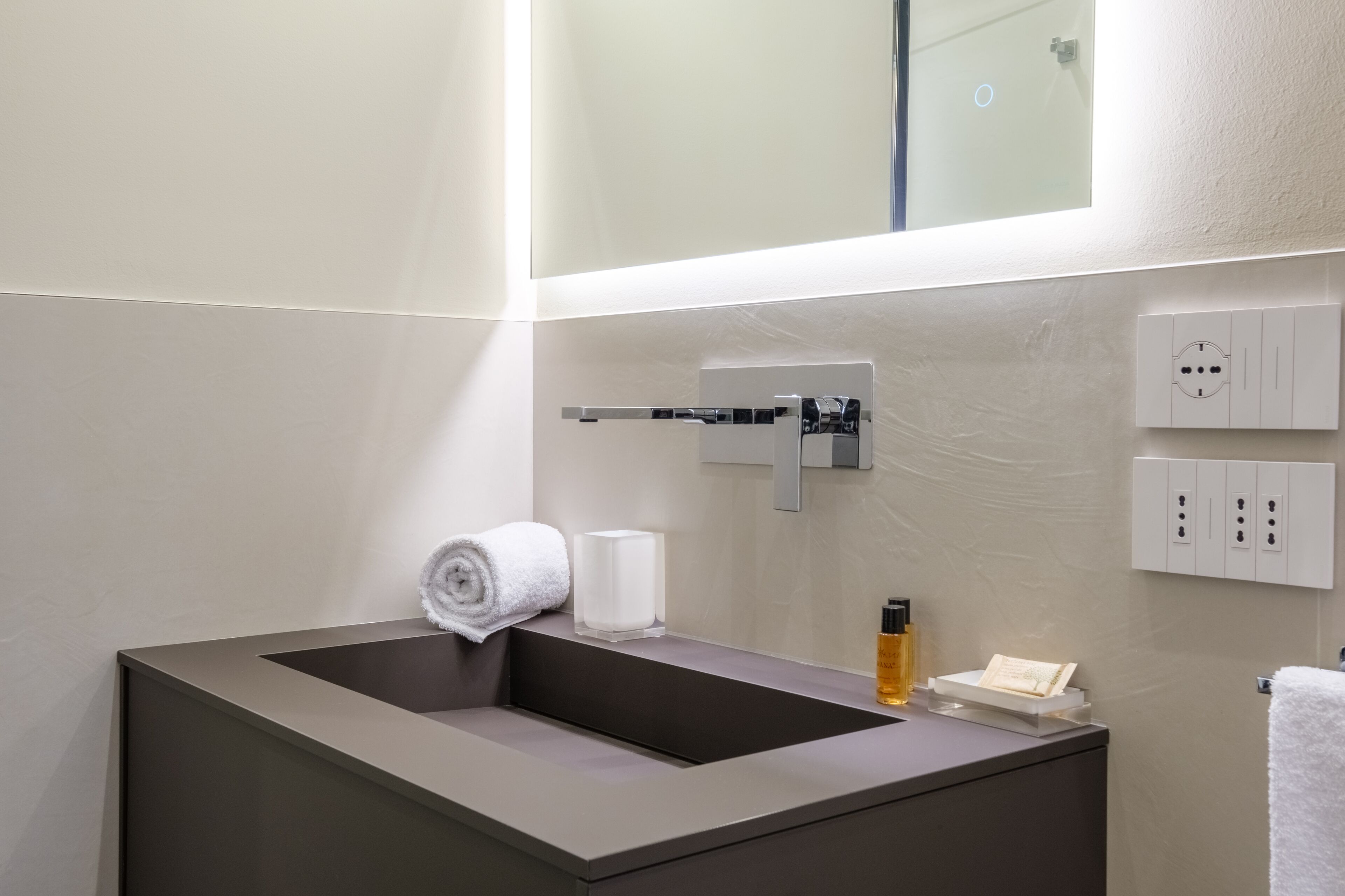 Ein modernes Badezimmer mit einem großen Waschbecken, einem Handtuch und Toilettenartikeln.