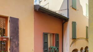 A narrow street with buildings featuring arched doorways and shutters. - Golden Suite by Studio Vita (Bologna)