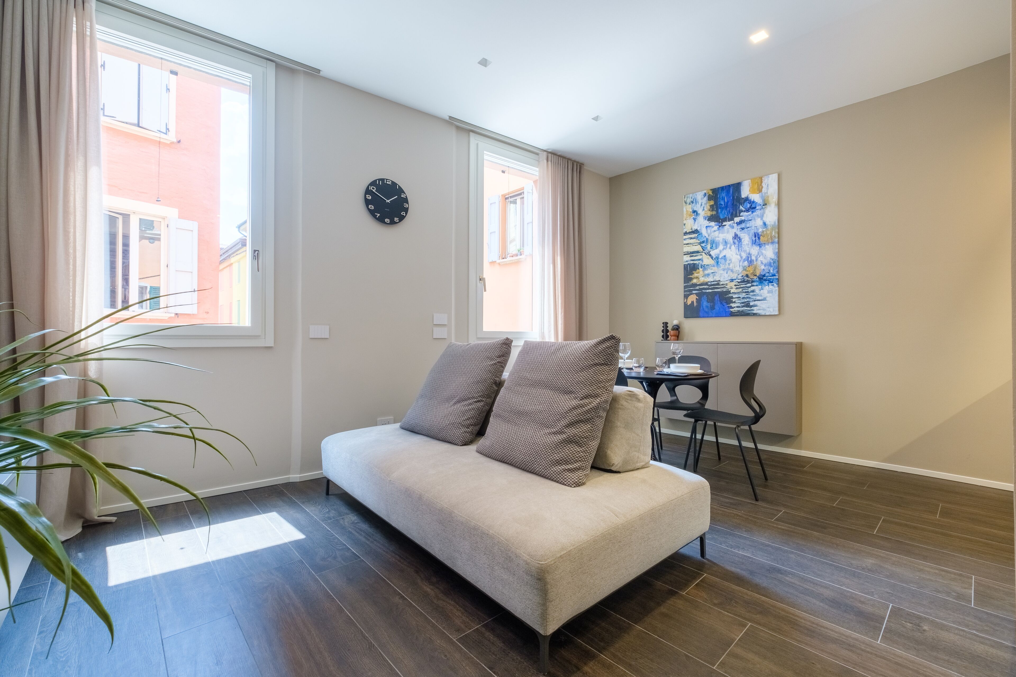 Ein modernes Wohnzimmer mit einer Couch, einem Essbereich mit Tisch und Stühlen sowie einem großen Fenster mit Vorhängen.