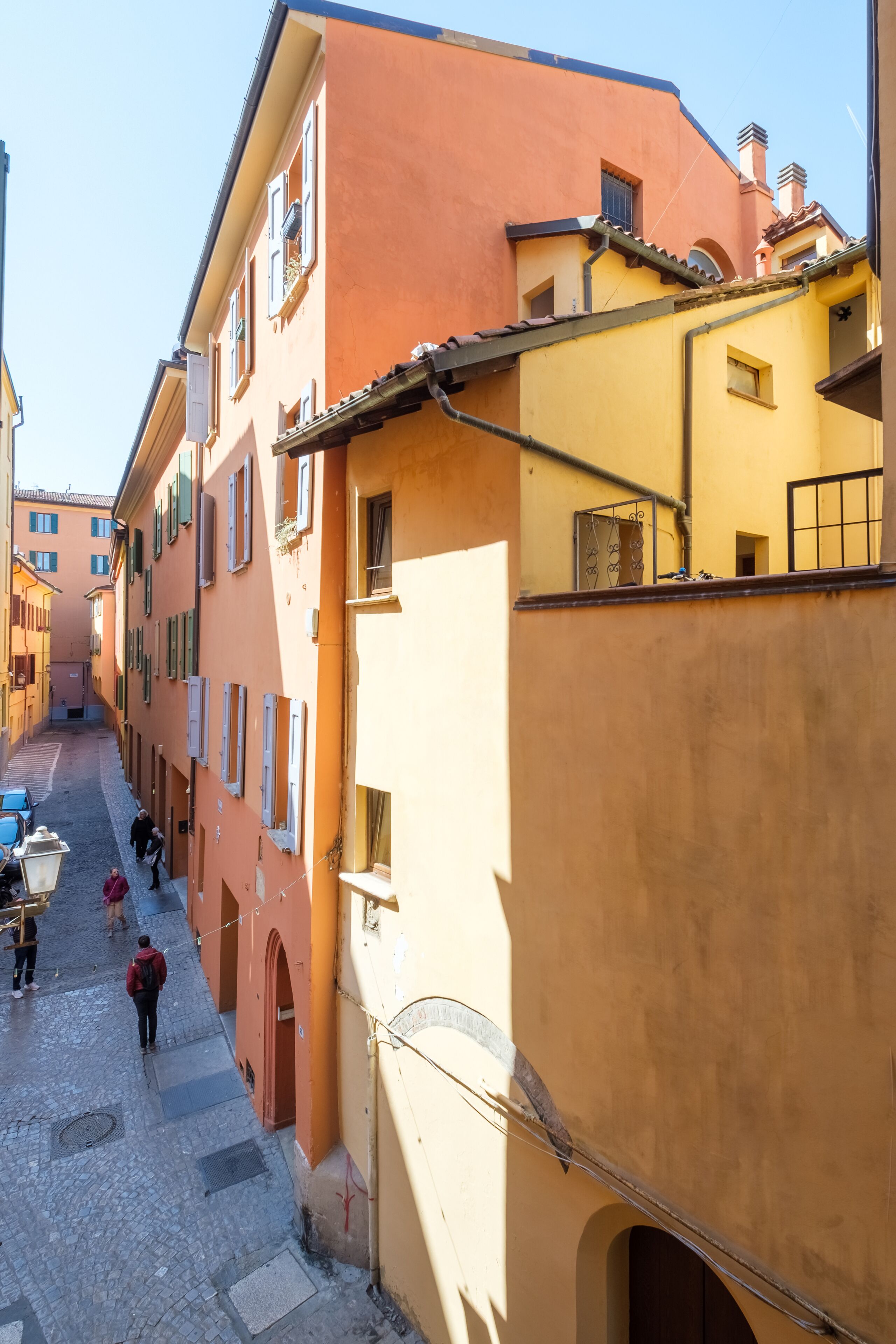 A narrow street with buildings on either side, featuring a mix of architectural styles and colors.