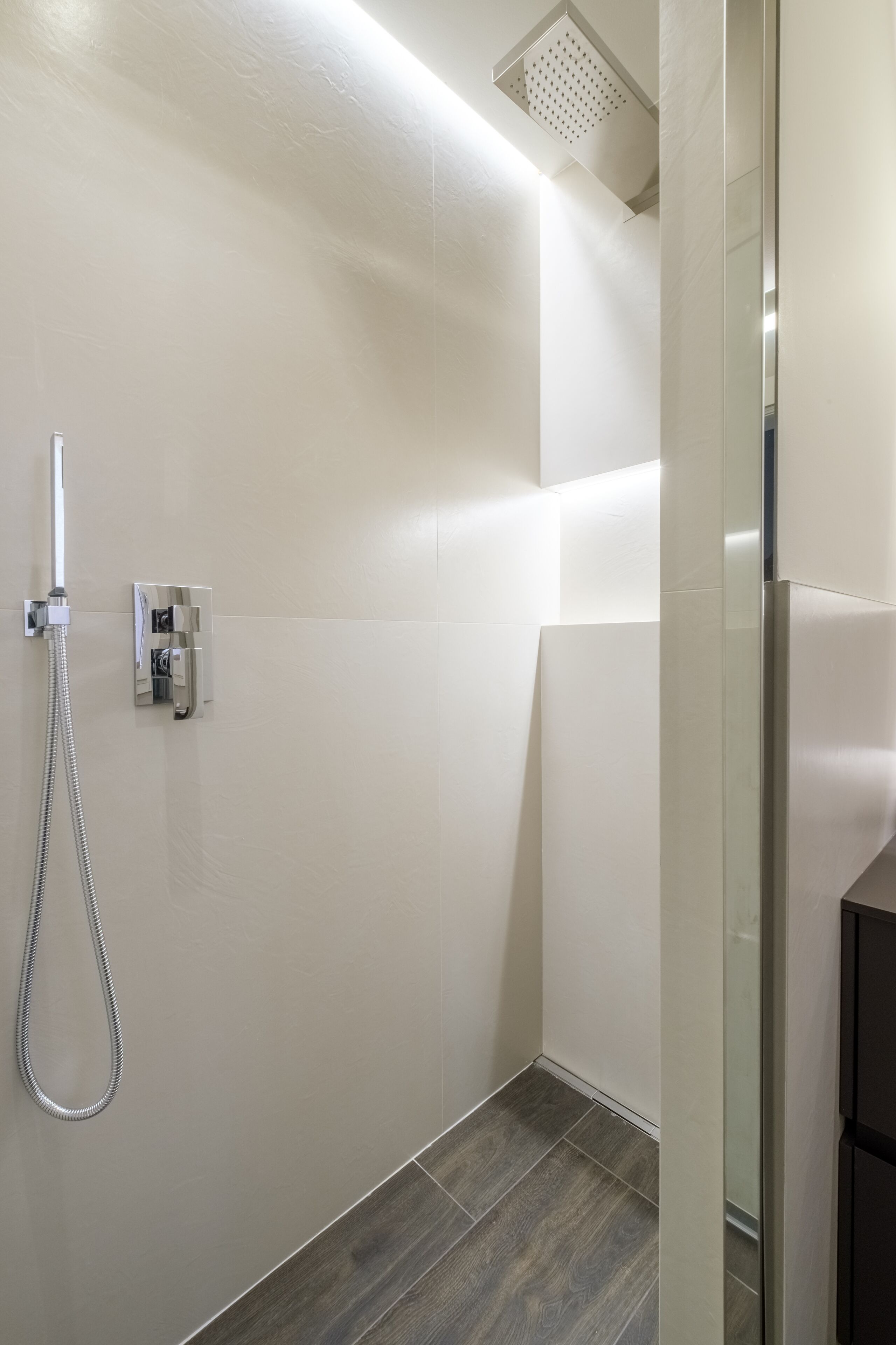 Un baño moderno con ducha, panel de control y mampara de vidrio.