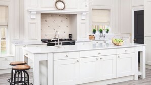 A spacious kitchen with a large island, white cabinetry, and pendant lighting.