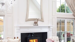 A spacious living room with a fireplace, elegant furniture, and a large mirror.