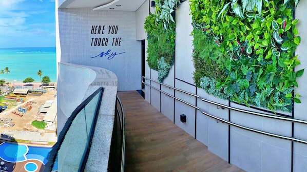 A modern hotel interior with a staircase leading to a balcony overlooking the ocean.