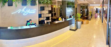 A reception desk with a neon sign, potted plants, and a modern interior design.