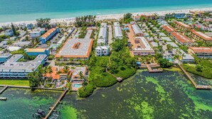 Vista aérea de um resort à beira-mar, com vários edifícios, uma praia e um porto de iates.