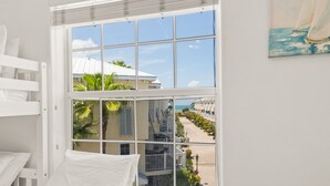 Quarto com uma grande janela que oferece vista para a praia e um edifício de hotel.
