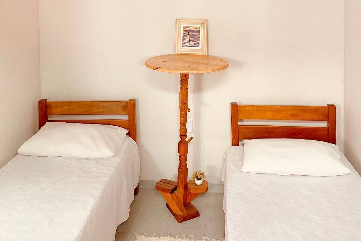 Two single beds with wooden headboards, a small round wooden table with a picture frame, and a white rug on the floor.