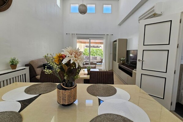 A dining area with a table set for four, a wicker centerpiece, and a view to the outside.