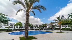 A pool area with palm trees, a clear sky, and white buildings in the background. - Villa with private pool and jacuzzi - EN10LT (Torre-Pacheco)