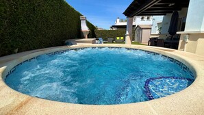 A hot tub surrounded by a tiled deck, with a hedge and a building in the background. - Villa with private pool & jacuzzi - CA27LT (Torre-Pacheco)