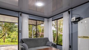 A room with a grey sofa, a wooden table, and a white refrigerator. - Uncle Carlos's house (La Tigra)