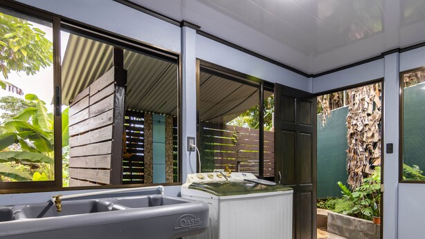 A bathroom with a bathtub, a shower, and a sink. There is a window with blinds, a door, and a view of the outside. - Uncle Carlos's house (La Tigra)