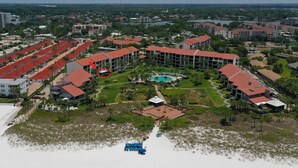 Vista aérea de un resort con varias construcciones, una piscina central y una zona de playa.