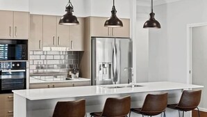 A modern kitchen with a central island, stainless steel appliances, and pendant lighting. - Private Mudjimba Beach Abode (Mudjimba)