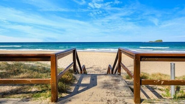 A wooden boardwalk leading to a beach with a clear view of the ocean and a small island in the distance. - Private Mudjimba Beach Abode (Mudjimba)