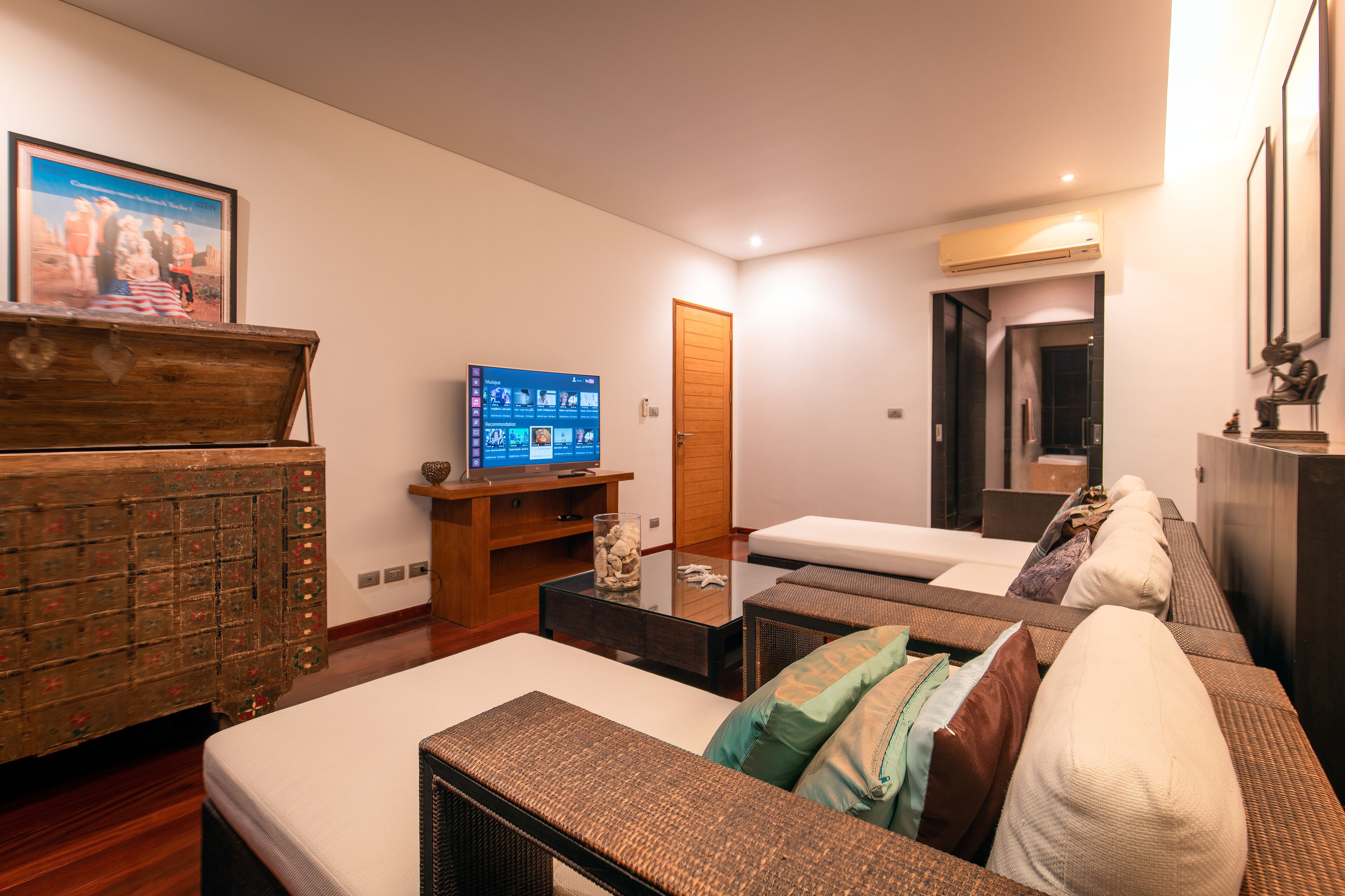 A hotel room with two beds, a wooden dresser, a television, and a door leading to a bathroom.