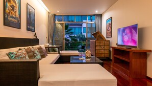 Quarto de hotel moderno com uma cama grande, um sofá, uma TV e vista para o exterior.