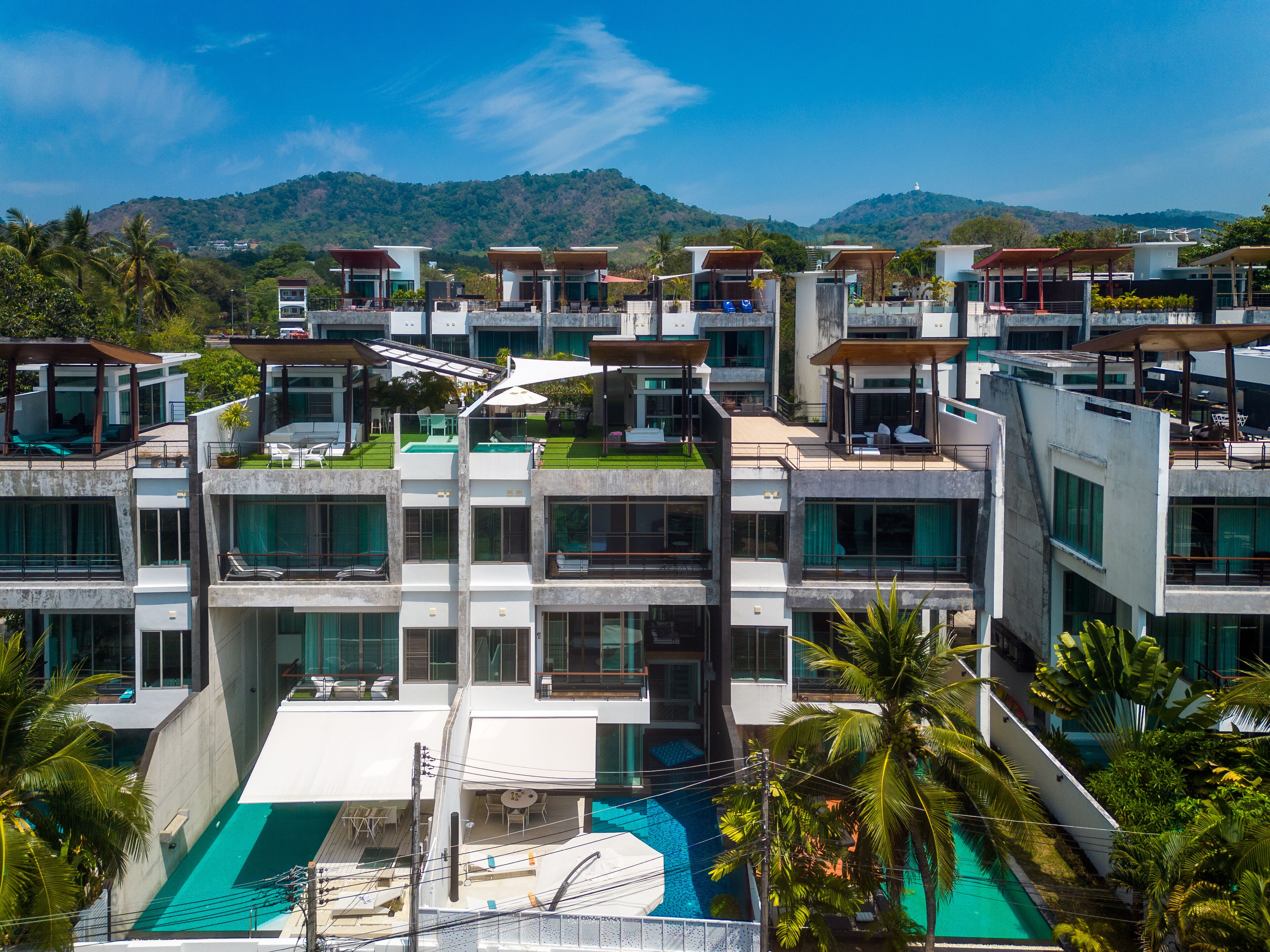 A modern multi-story hotel with a rooftop pool and lush greenery.