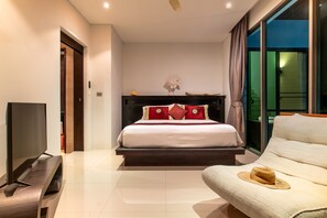 A modern hotel room with a large bed, a flat-screen TV, a sofa, and a view of the city through large windows. - Villa Sabine private pool 4br seaview (Rawai)