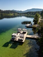 Un muelle a orillas de un lago con aguas cristalinas, rodeado de colinas boscosas.