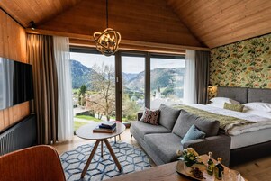 Un dormitorio moderno con una cama grande, un sofá, una televisión y vistas a la montaña.