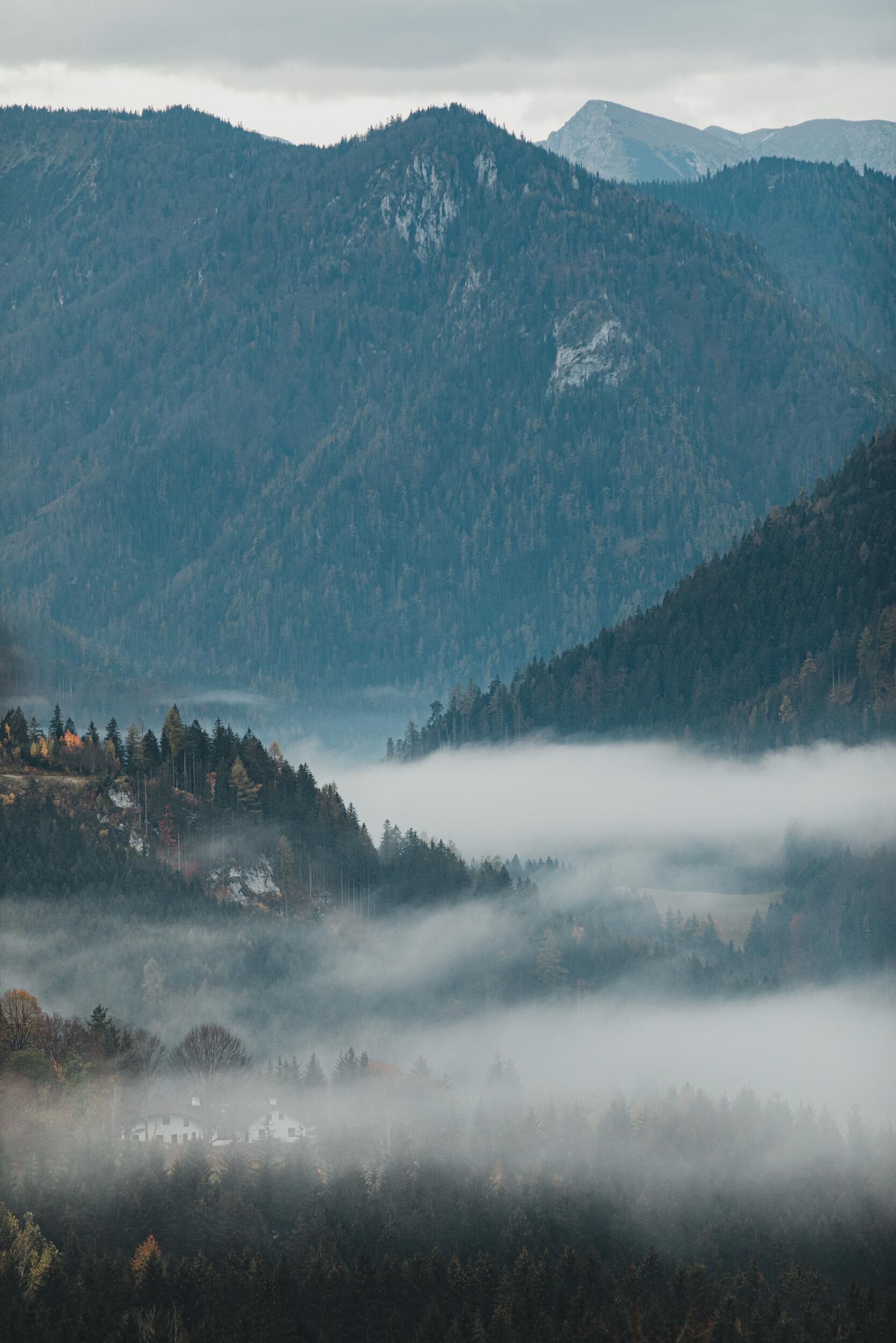 A mountainous landscape with a valley and a house in the foreground.
