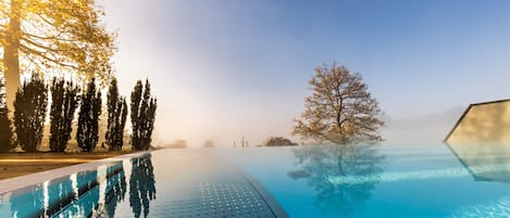 Una piscina al aire libre, sombrillas, sillones reclinables de piscina