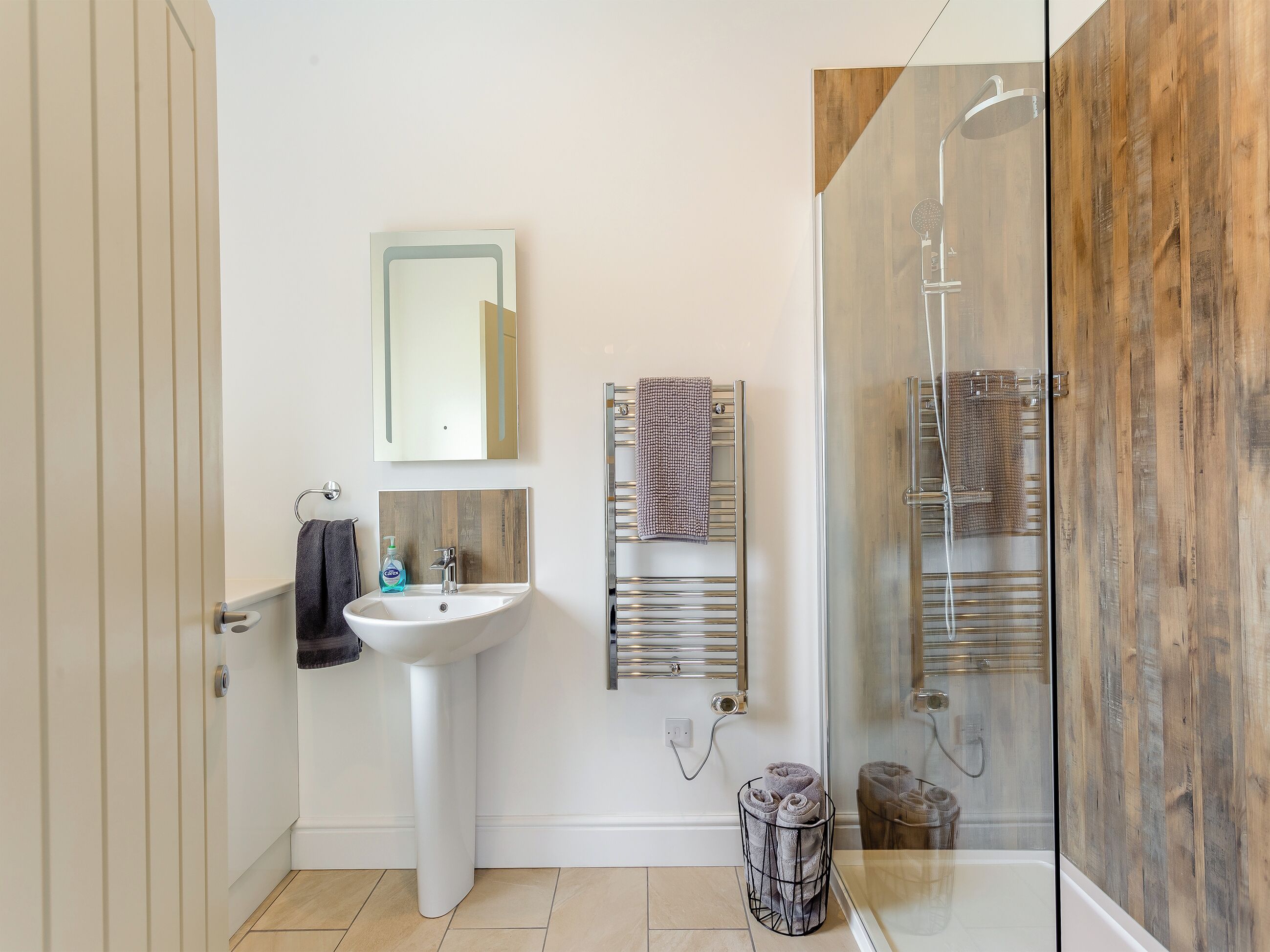 Ein modernes Badezimmer mit einem Standwaschbecken, einem Spiegel, einem Handtuchhalter und einer Duschkabine.