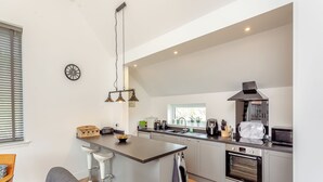 Una cucina moderna con isola centrale, forno integrato ed elettrodomestici in acciaio inossidabile.