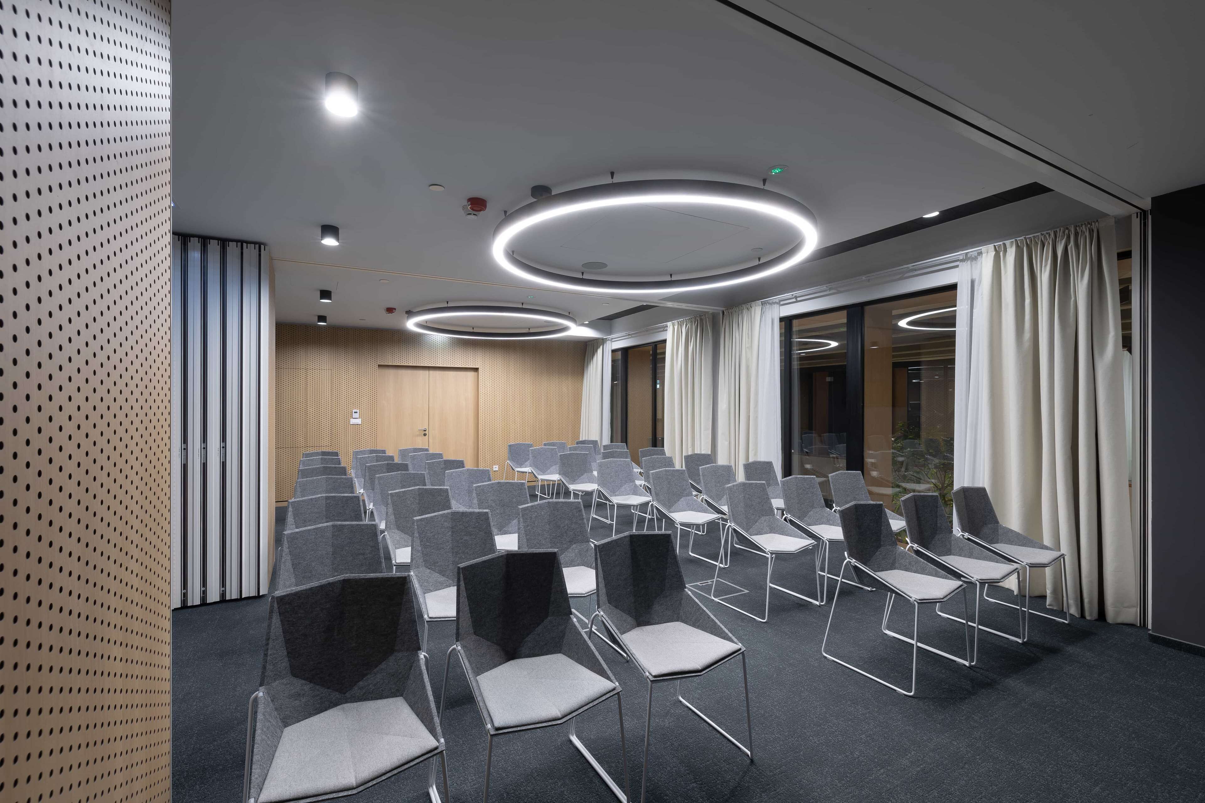 A conference room with rows of chairs, a wooden door, and a large window with curtains.