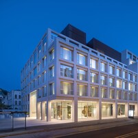 A modern building with multiple floors, large windows, and a well-lit entrance.