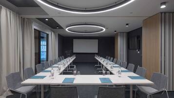 A conference room with a long table, chairs, and a projector screen.