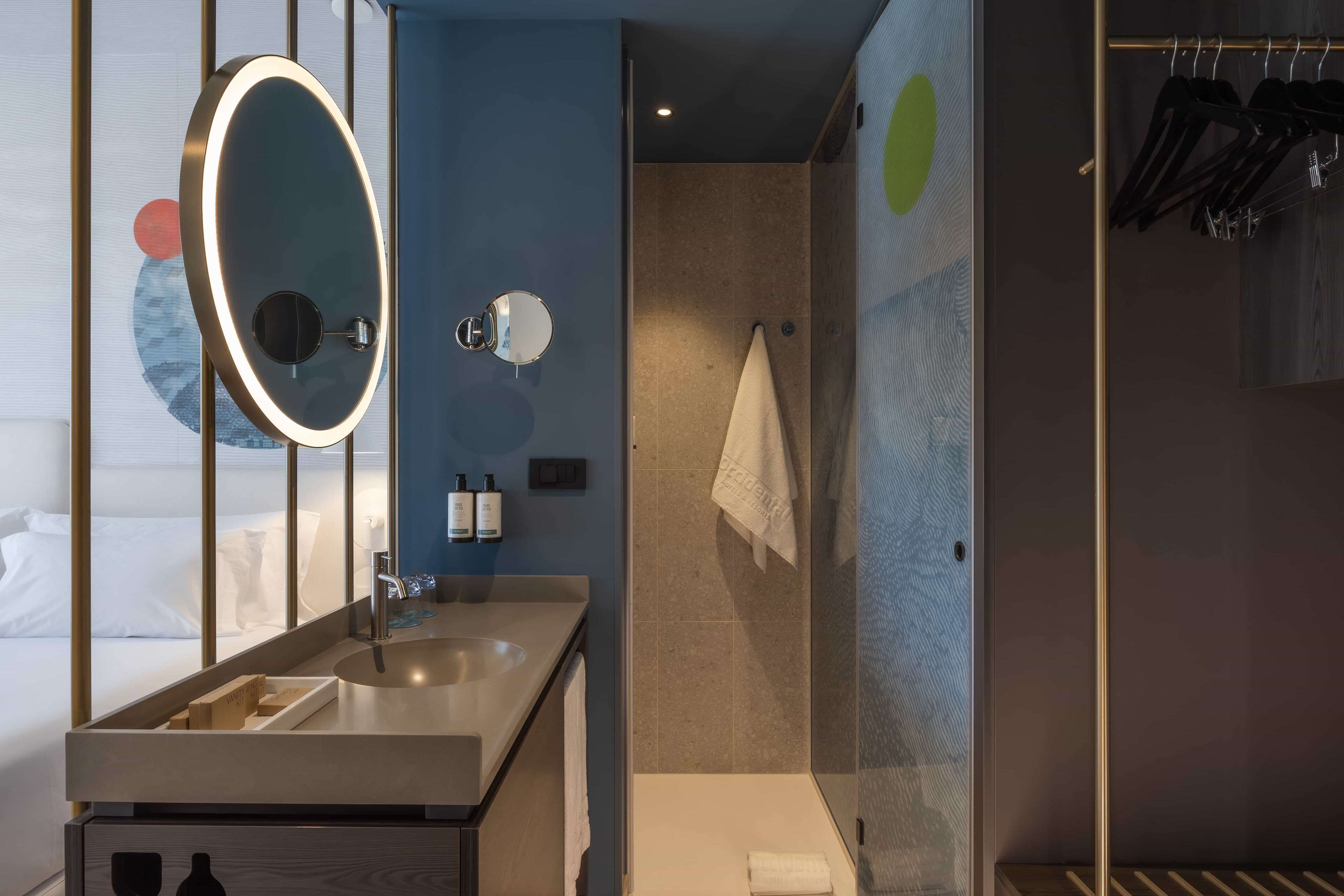 A modern bathroom with a large mirror, a sink, and a shower area.